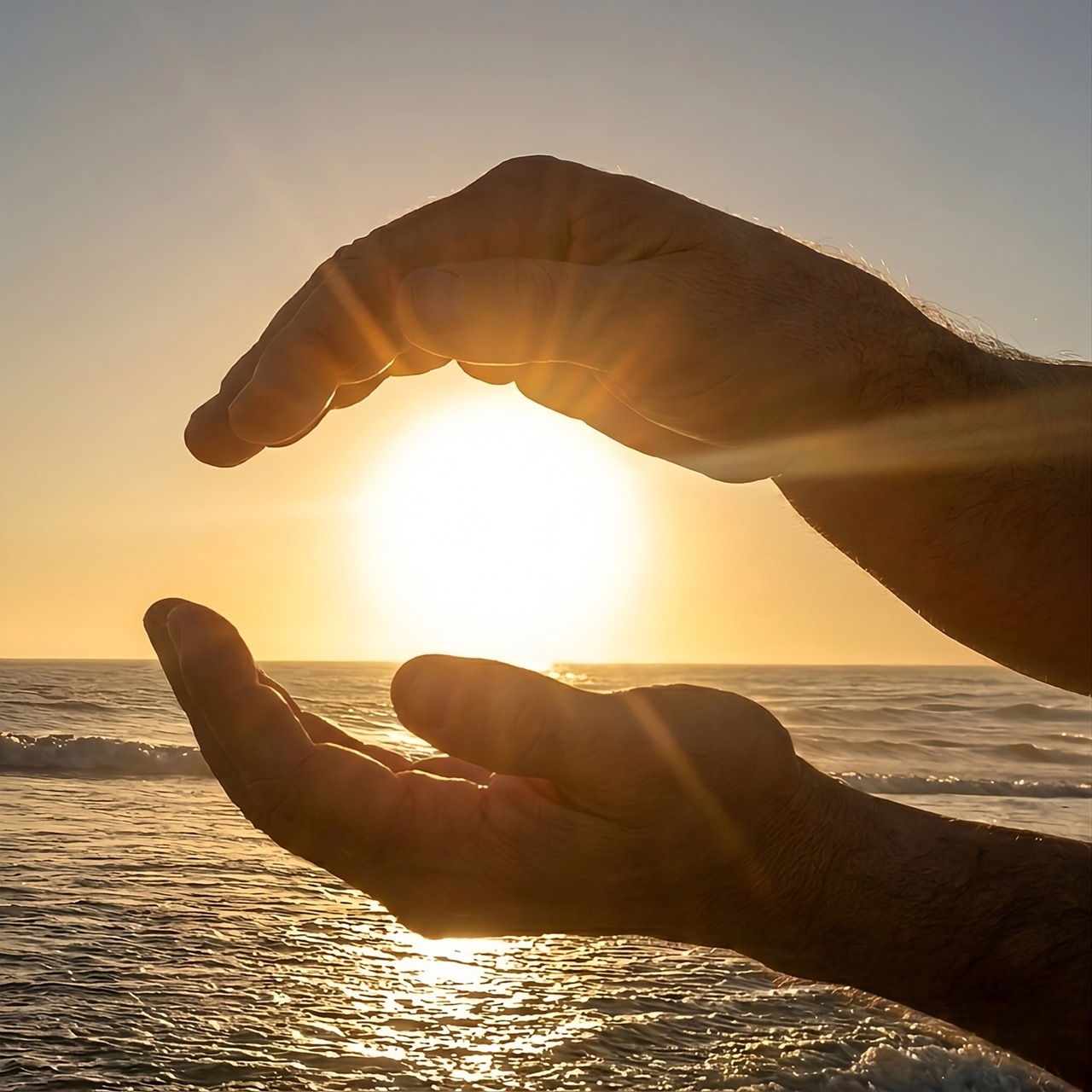 Dos manos sosteniendo la luz del sol sobre el mar, para Reiki